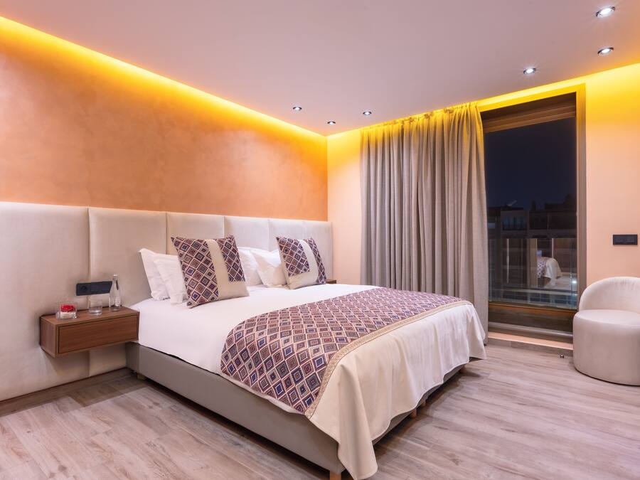 A modern bedroom with a large bed, bedside table, and a chair.