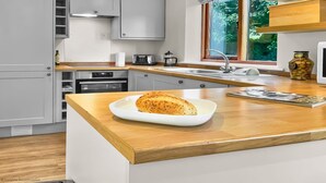 A modern kitchen with a wooden countertop, a loaf of bread on a white plate, and a magazine.