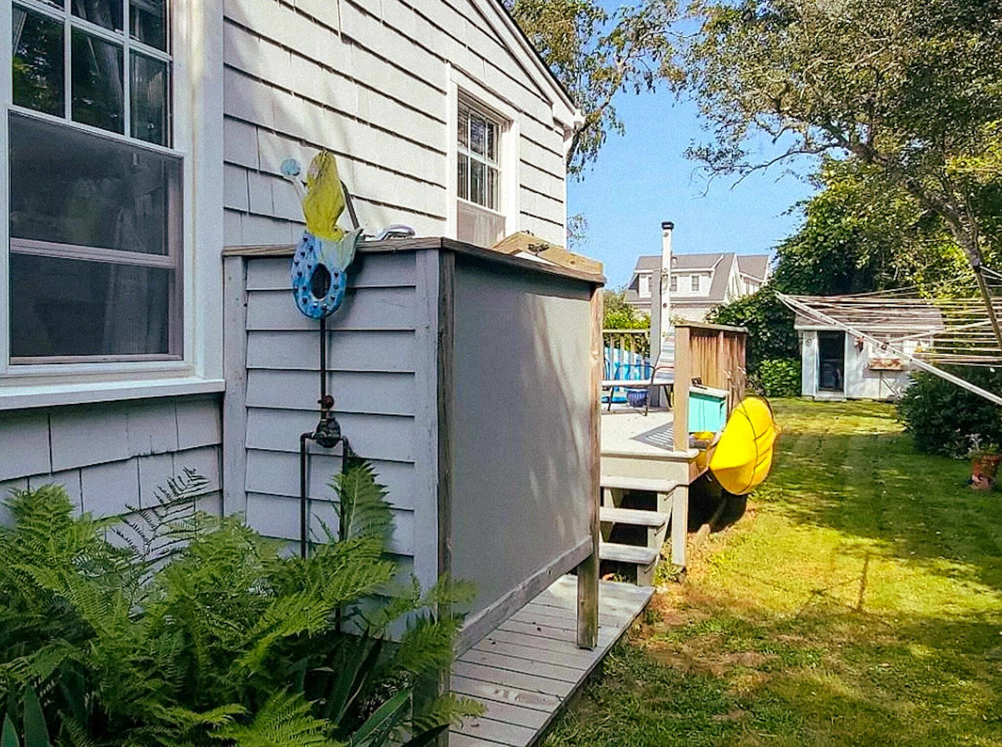A house with a covered porch, a birdhouse, and a fenced yard.