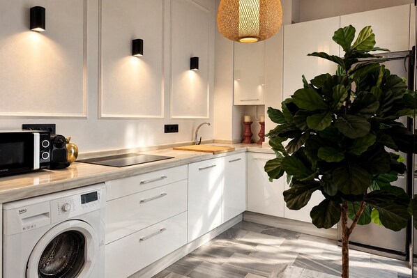 Une cuisine moderne avec des meubles blancs, un lave-linge encastré, un four à micro-ondes et un évier.