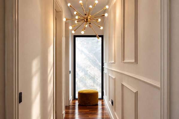A hallway with a modern chandelier, a wooden floor, and a door with frosted glass. - Genteel Home Corral del Rey II (Seville)