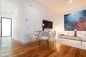 Un salon moderne comprenant un coin repas, un téléviseur à écran plat et un grand tableau abstrait.