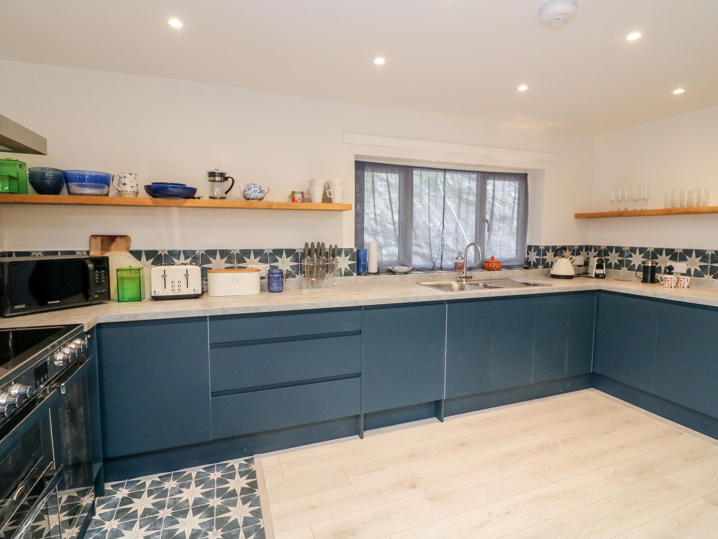 A modern kitchen with blue cabinets, a microwave, a toaster, and a sink.