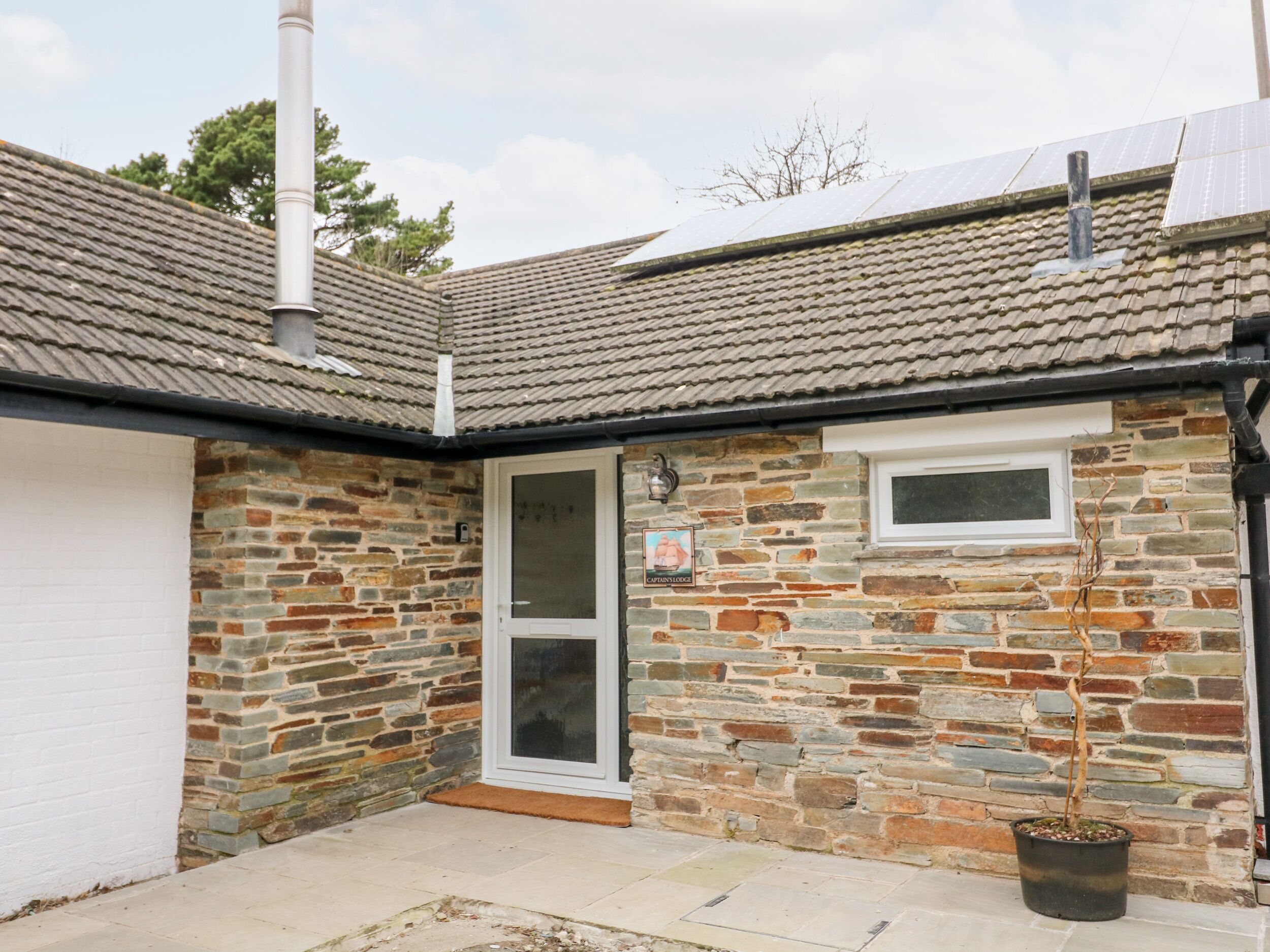 A stone building with a tiled roof, a glass door, and a small window.