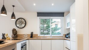 Une cuisine moderne dotée d’un plan de travail en bois, d’un four encastré, d’un évier et d’une fenêtre donnant sur les arbres.