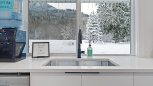 A kitchen with a large water dispenser, a framed certificate, and a window with a snowy mountain view.