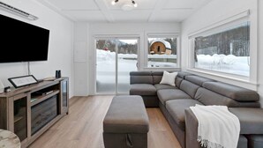 A modern living room with a sectional sofa, a flat-screen TV, and a wooden entertainment unit.