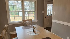 A dining room with a large table, chairs, a chandelier, and windows with views of the outdoors. - Deluxe! New Cozy Apt Near Downtown, Ready for Families and Business Travelers.

 (Raleigh)