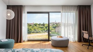 A modern hotel room with a large sliding glass door, a round ottoman, a teal armchair, and a bed with a floral bedspread. - Villa Terra Adria - Four Bedroom Villa, Sleeps 8 (Bale)
