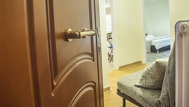 A hotel room with a closed door, a bed with a grey blanket, and a small table with a chair. - Fionia In Gazi- Athens Center Apartment Free Wifi (Athens)