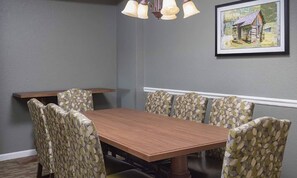 A dining area with a wooden table and patterned chairs, a hanging light fixture, and a framed picture on the wall. - WOW! Smoky Mountains, 1 Bedroom Deluxe

 (Sevierville)