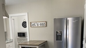Una cocina compacta con un refrigerador de dos puertas, un microondas y una mesa de madera.