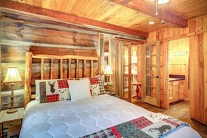 A wooden cabin room with a bed, wooden walls, a door, and a window.