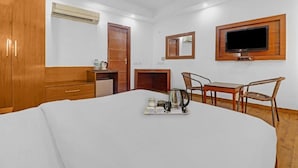 Ein Hotelzimmer mit Bett, Schreibtisch, Stuhl, Fernseher und Klimaanlage.