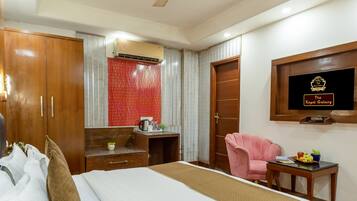 A hotel room with a bed, a desk, a chair, a television, and a ceiling fan.