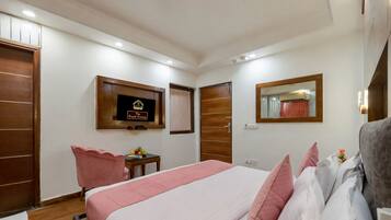 A hotel room with a bed, a desk, a chair, a mirror, and a television on the wall.