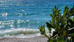 A beach with pebbles, clear blue water, and mountains in the background. - With sea view only 250 metres to the beach (Baska)