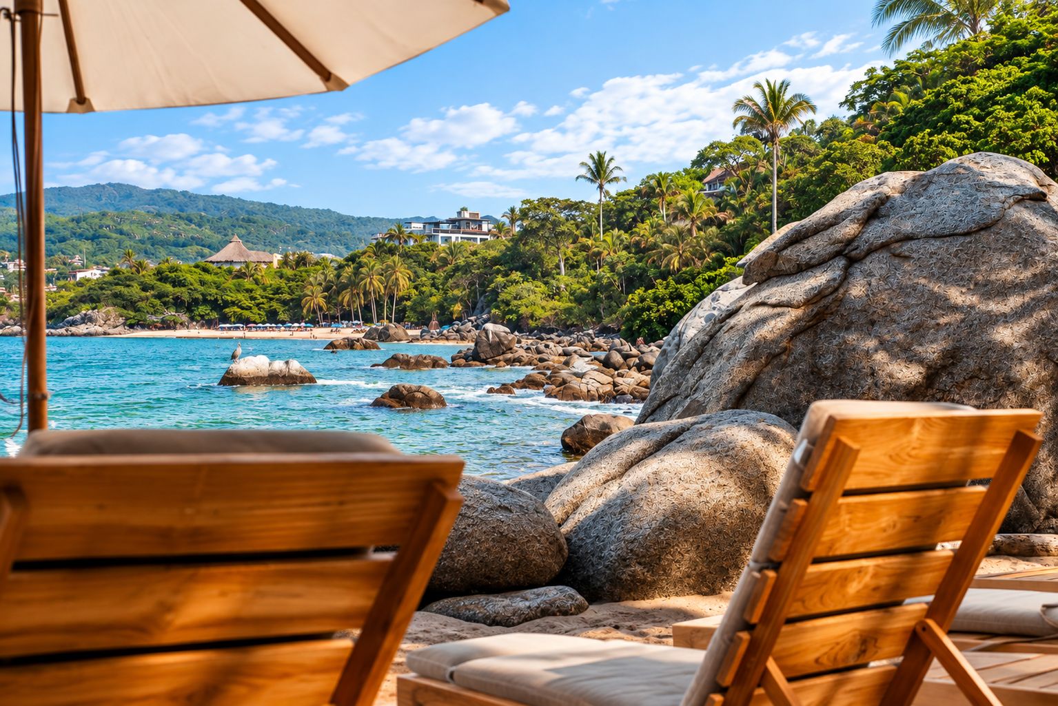 A beachside view with large rocks, a wooden chair, and a clear blue sky.