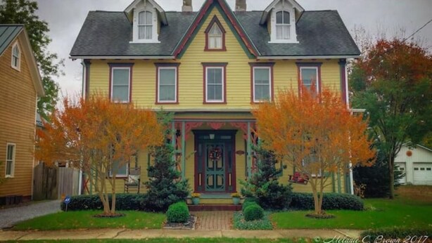 A two-story house with a gabled roof, a front porch, and a front door with a decorative surround. - Guest Suite for up to 2 in a Victorian on the Chester River (Millington)