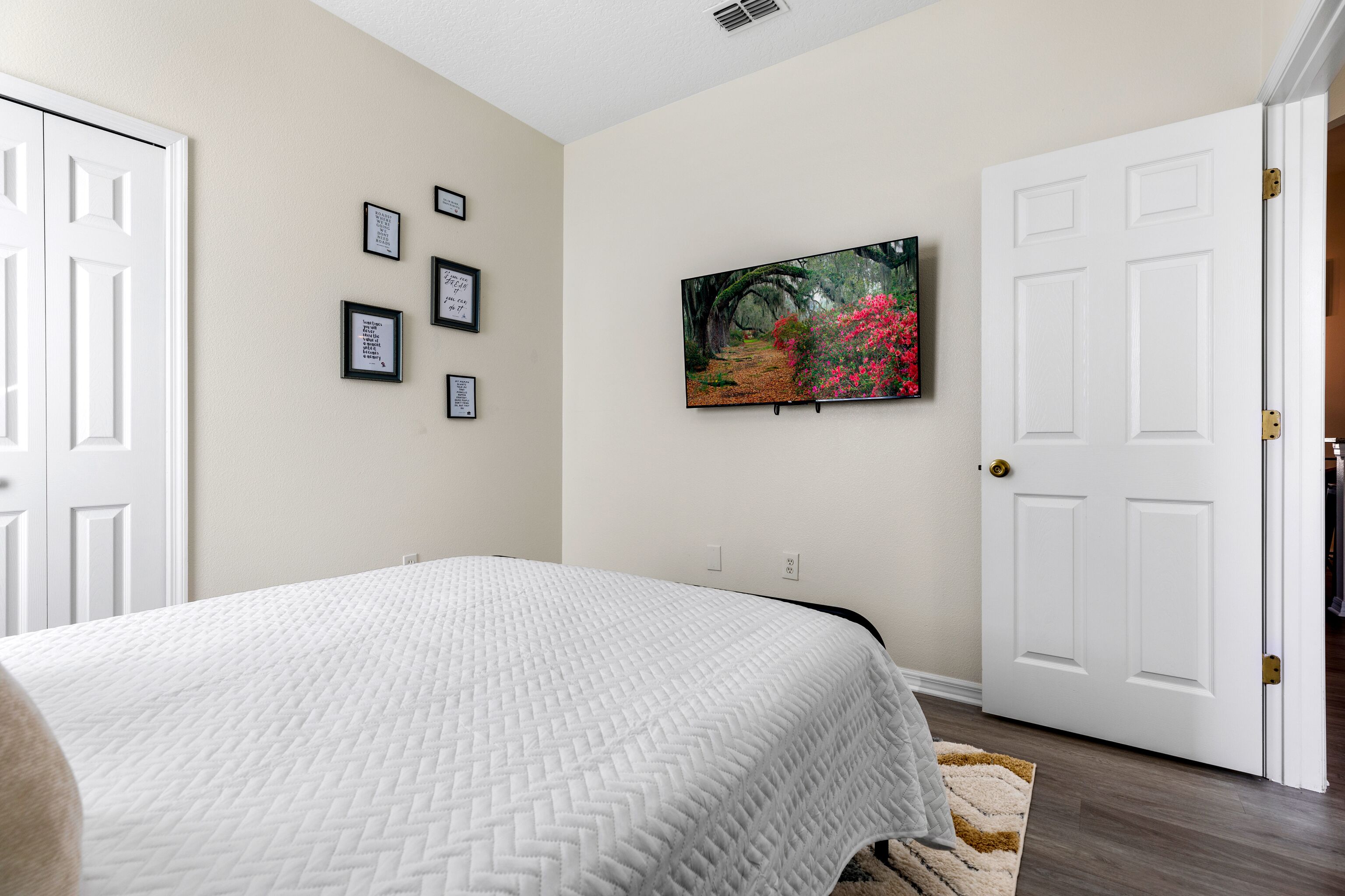 Um quarto com uma cama, uma porta branca, um quadro emoldurado e uma pintura na parede.