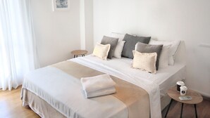 A neatly arranged bedroom with a bed, pillows, a bedside table, and a small round table with a cup and a remote control. - Filoenia In Center of Athens (Athens)