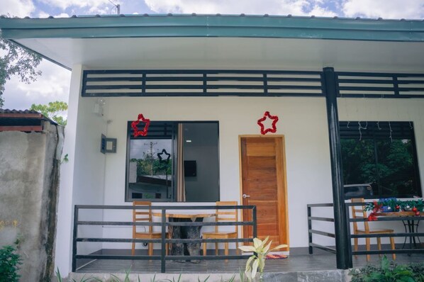 Situated in a residential area, this single-story building features a covered porch with a table and chairs.