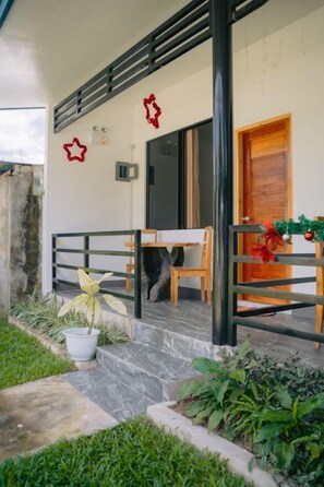 Relax in a serene outdoor space with a bench and table, surrounded by lush greenery and a charming entrance.