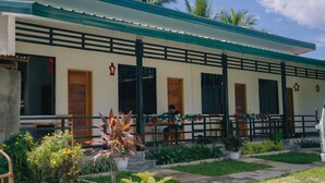 A building with a covered outdoor seating area, a wooden door, and a balcony.