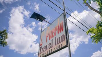 Une enseigne indiquant l’emplacement du L'Perrier Travel Inn, avec un numéro de téléphone à contacter.