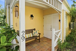 A porch with a bench, a door, and a wall-mounted light fixture. - Seaview Palms at Villa Madeleine – Private Pool – East End St. Croix (Christiansted)