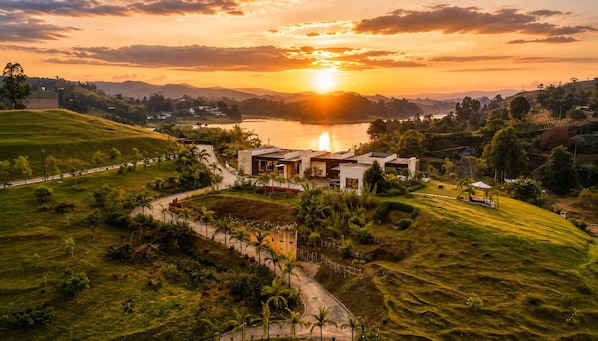 A modern house with a garden, a pathway, and a view of the sunset over a lake.