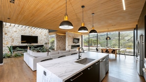 A modern kitchen with a large island, built-in appliances, and a stone accent wall.