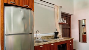 A compact kitchen with a stainless steel refrigerator, double sink, wooden cabinets, and a microwave. - Casa Huapango Studio suite with kitchenette. (Bucerias)