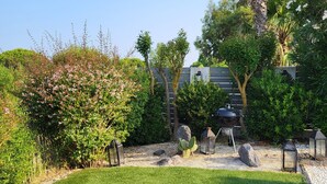 A well-maintained garden with a variety of plants and a barbecue area.