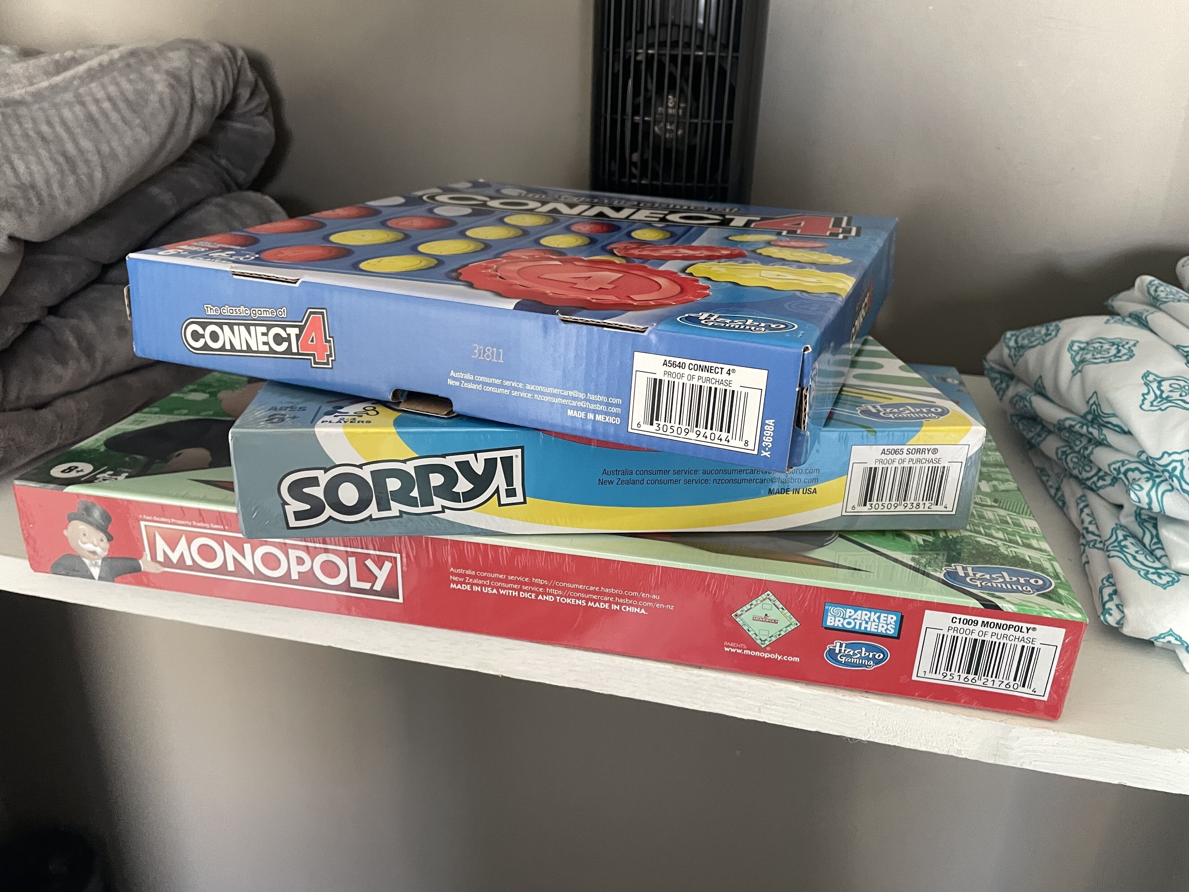 A shelf with board games including Connect 4, Sorry!, and Monopoly.