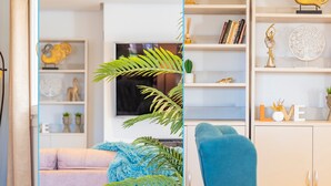 Un salon moderne avec un fauteuil bleu, un canapé et une bibliothèque remplie d’objets décoratifs.