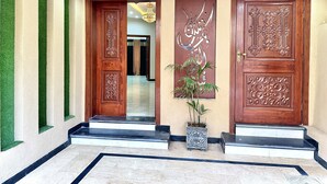 A foyer with two ornate wooden doors, a ceiling fan, and a potted plant.