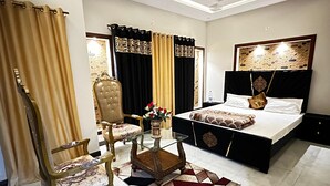 A bedroom with a bed, a chair, a table, and curtains.