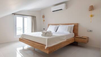Et moderne hotelværelse med en træseng, hvide sengetøj, et lille natbord og en vægmonteret aircondition.