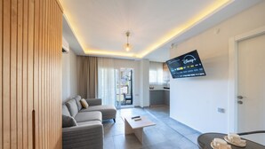 Ein modernes Wohnzimmer mit einer Couch, einem Couchtisch und einem an der Wand befestigten Flachbildfernseher.