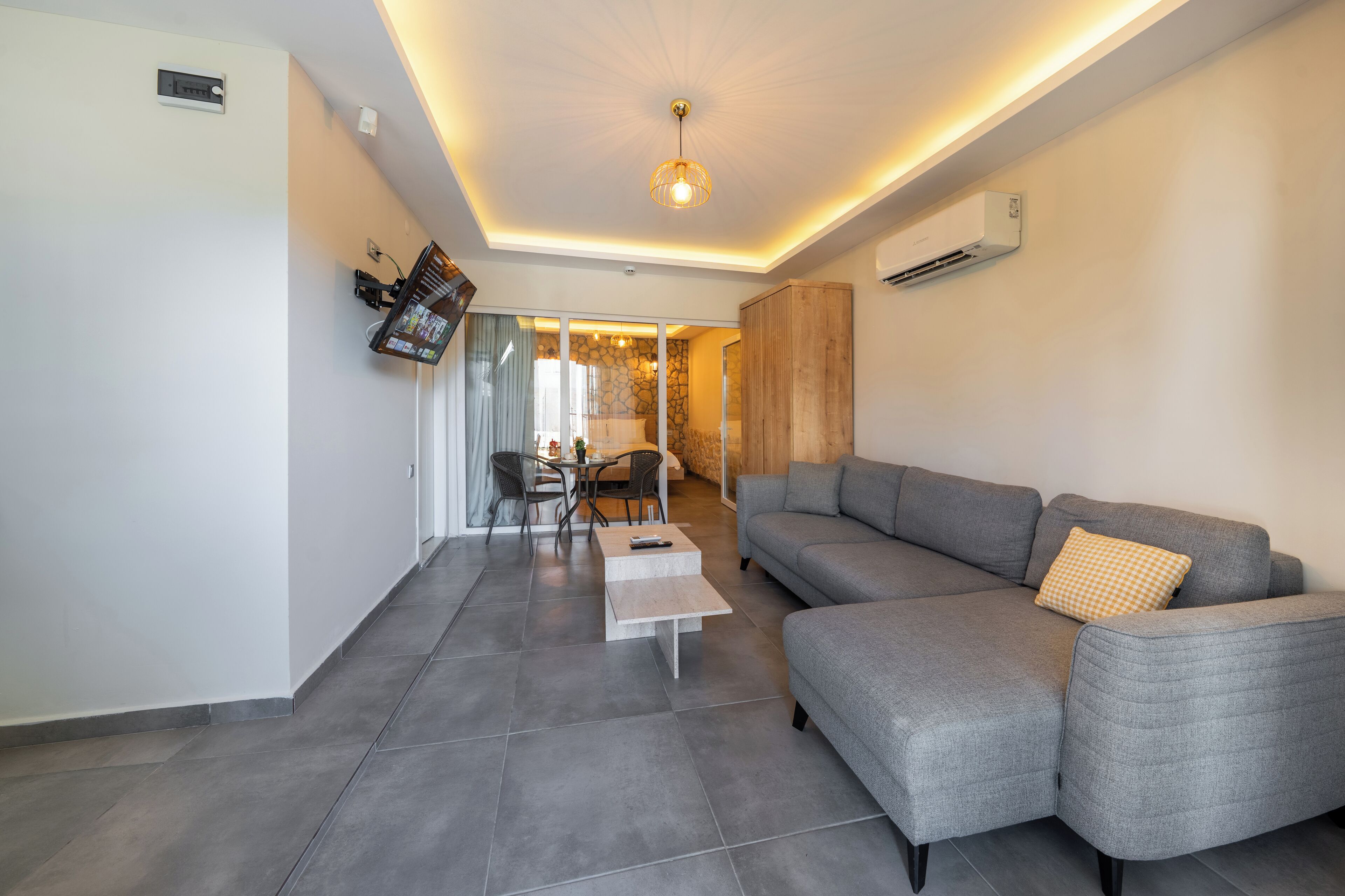 Un salon moderne avec un canapé d’angle gris, une petite table basse et un coin repas comprenant une table et des chaises.