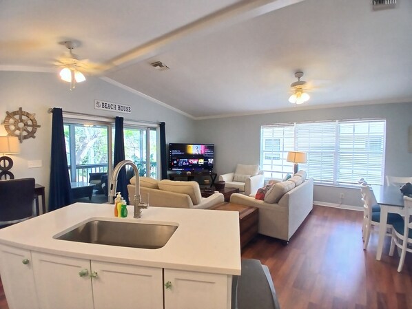 A living room with a sofa, TV, and a sign reading "Beach House".