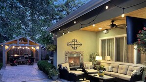 A patio area with outdoor furniture, a stone fireplace, and string lights.