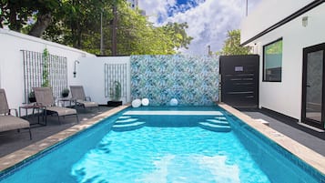 Una piscina al aire libre, sillones reclinables de piscina