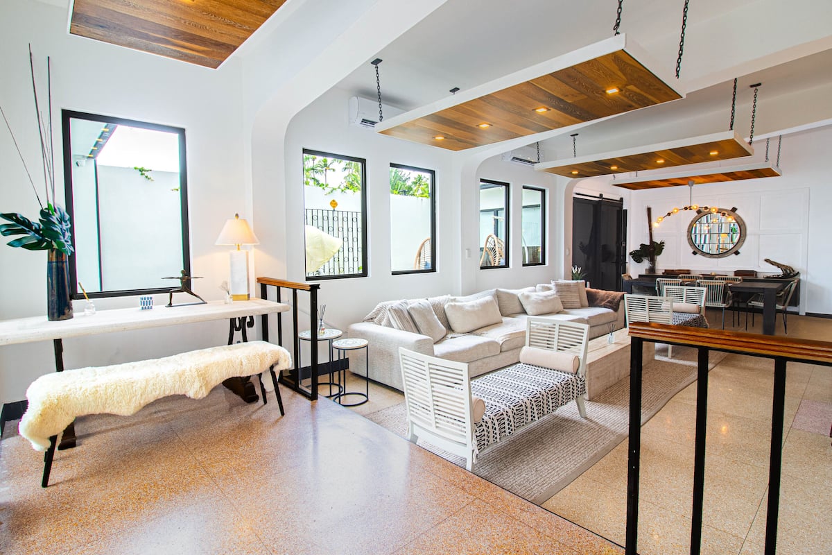 A spacious living area with a white sofa, a bench, and a dining table.