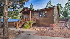 A wooden cabin with a porch and a staircase leading to the entrance.