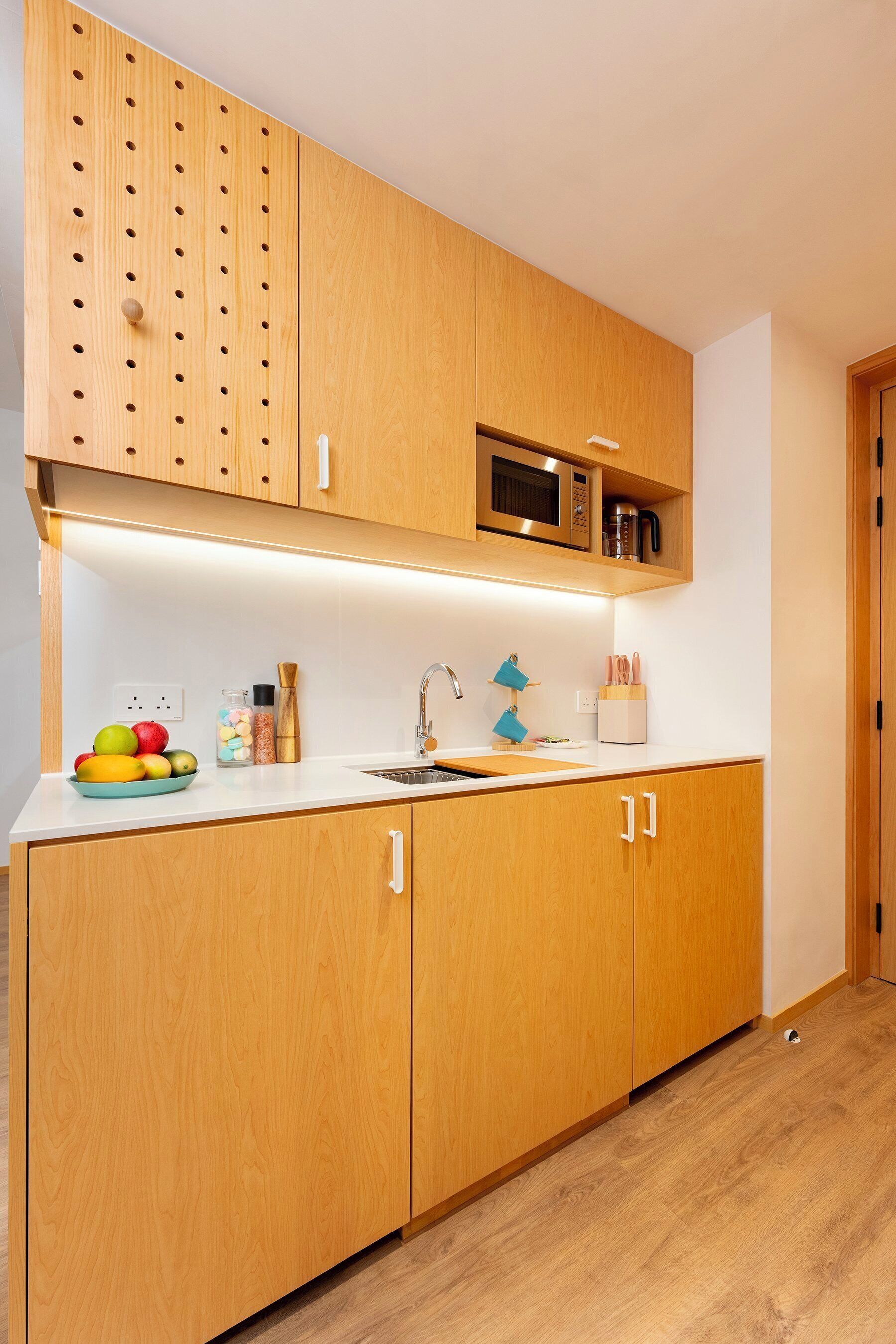 A modern kitchen with wooden cabinets, a microwave, and a sink.
