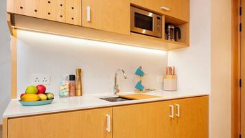 A modern kitchen with wooden cabinets, a microwave, and a sink.