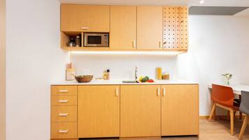 A modern kitchen with wooden cabinets, a microwave, and a dining area with a table and chairs.