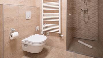 A modern bathroom with a toilet, a towel rack, and a shower area.